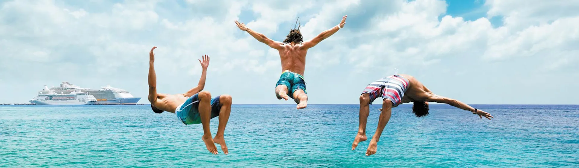 Tre killar hoppar i vattnet från en brygga i Cozumel, Mexiko.