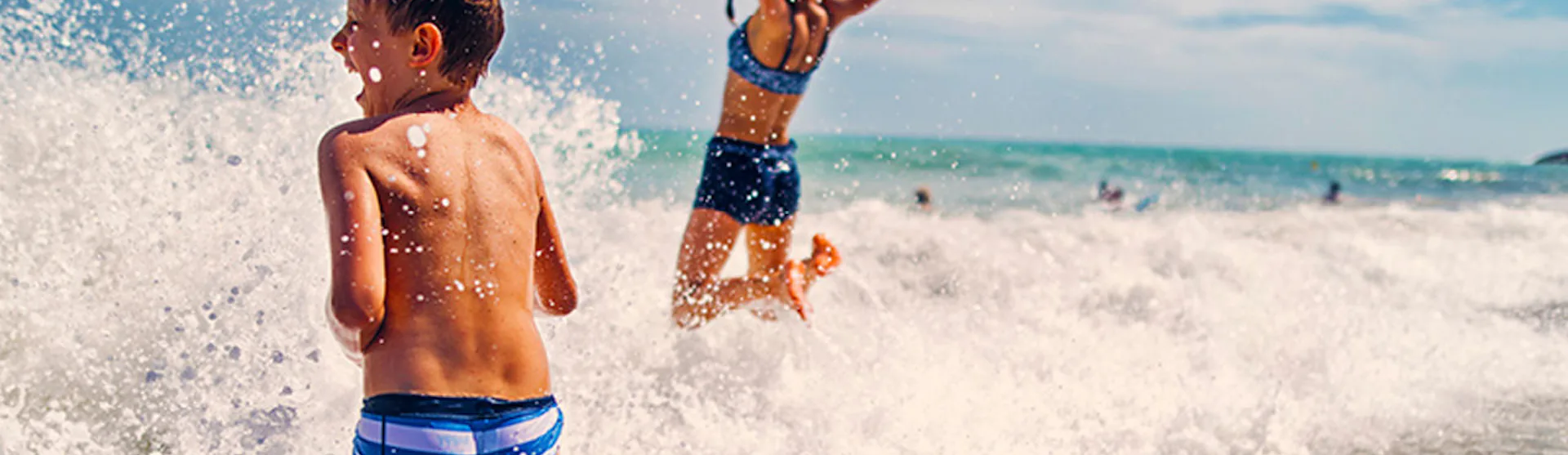 Kille och tjej som leker i vågorna.