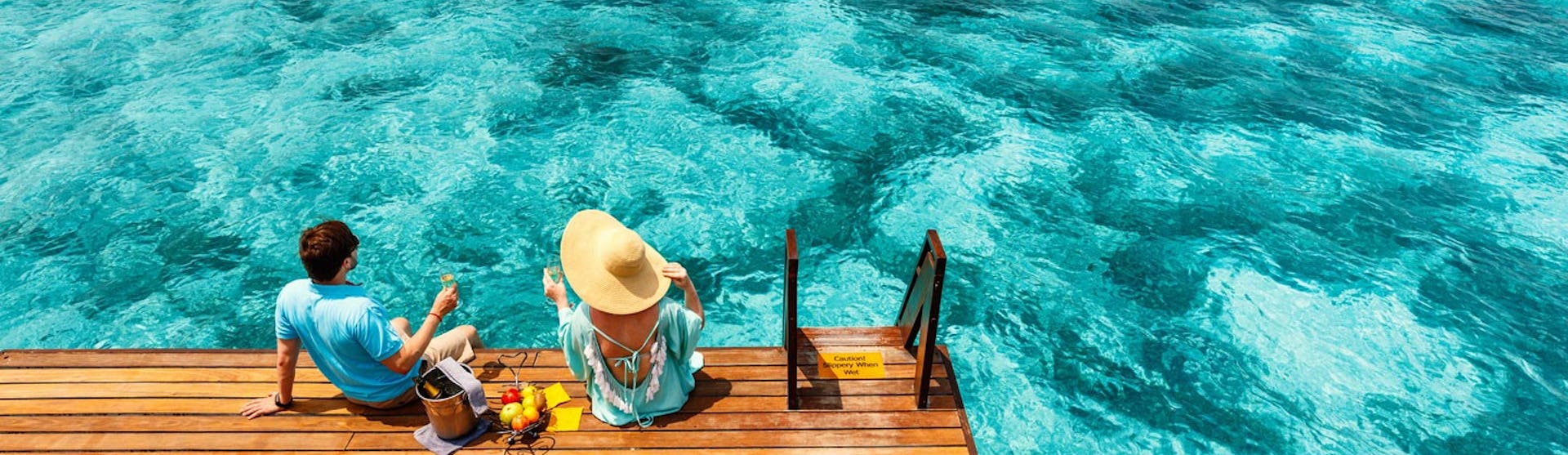 Par njuter av gott att äta och dricka på en brygga.