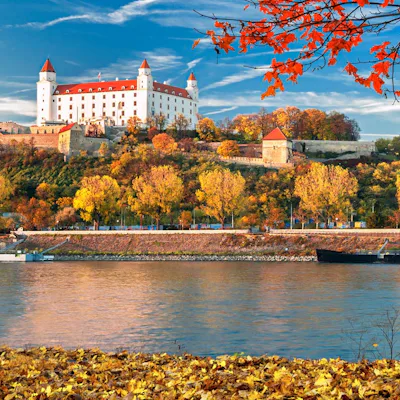 Bratislava slott i Slovakien, med vackert röda höstlöv i förgrunden.