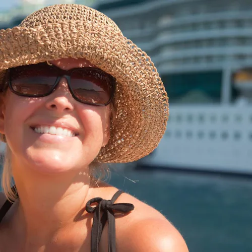 Glad kvinna framför ett kryssningsfartyg.