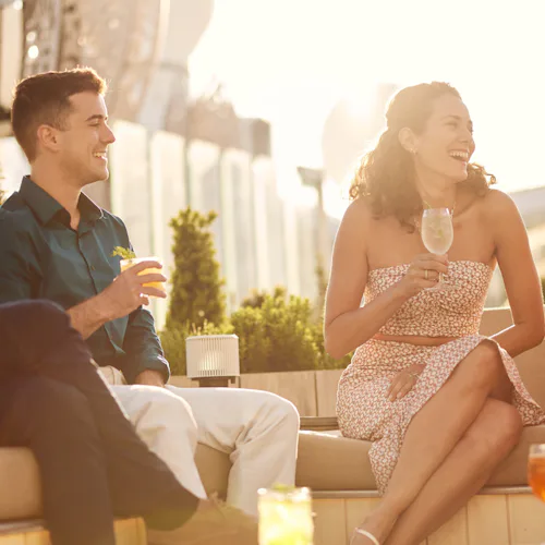 Glada gäster med drinkar på Rooftop Garden ombord på fartyget Celebrity Beyond.