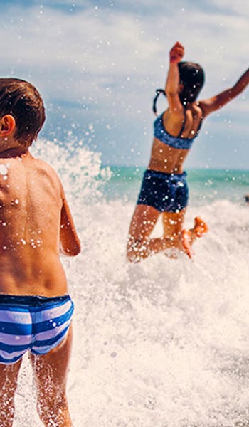 Kille och tjej som leker i vågorna.