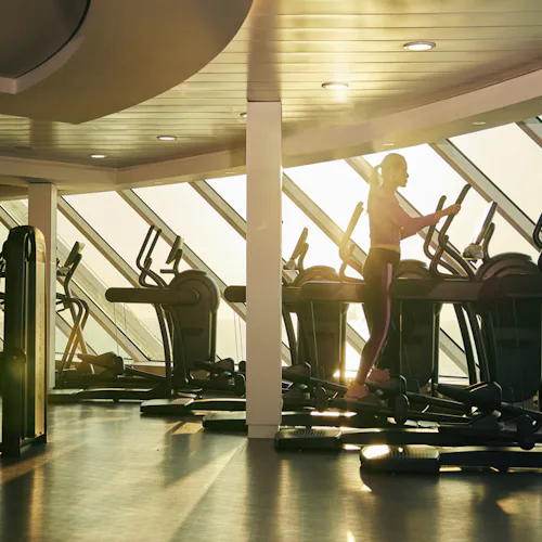 Kvinna på crosstrainer i Fitness Center ombord på fartyget Celebrity Beyond.
