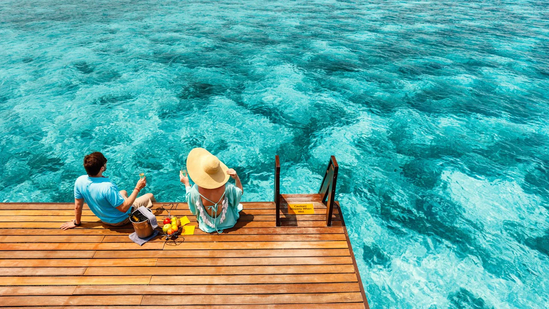 Par njuter av gott att äta och dricka på en brygga.