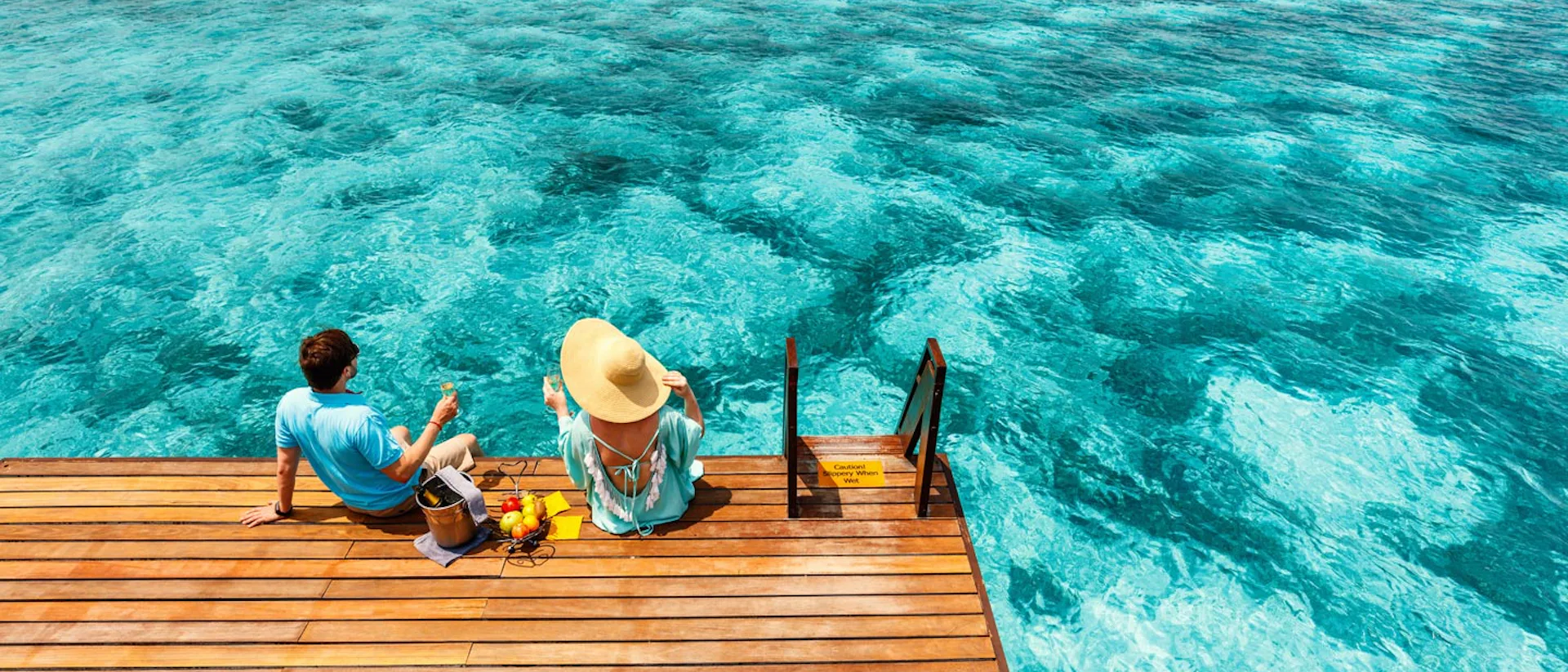 Par njuter av gott att äta och dricka på en brygga.