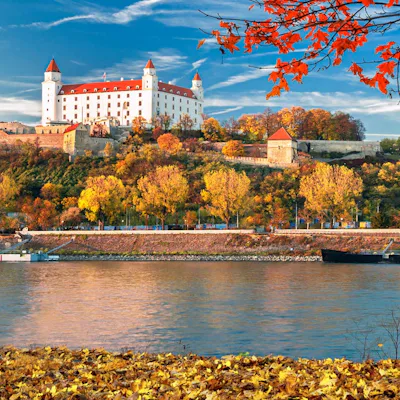 Bratislava slott i Slovakien, med vackert röda höstlöv i förgrunden.