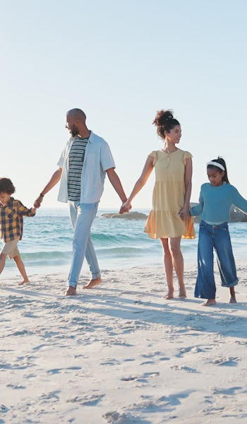 Stor familj håller hand på stranden.