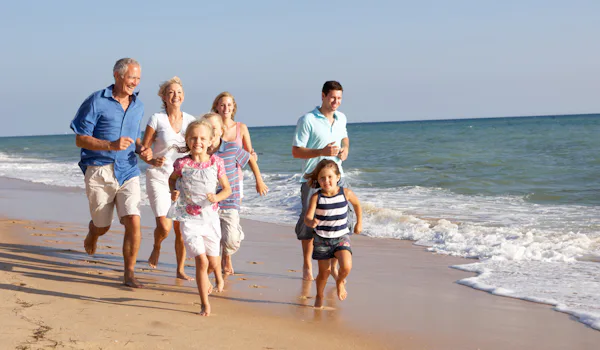 Familj i tre generationer, springandes på en strand.